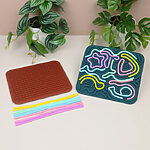 برد حسی آرامش‌بخش سیلیکونی دوطرفه کودک (اسباب‌بازی ضد استرس) کنار برگ سبز