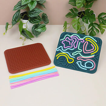 برد حسی آرامش‌بخش سیلیکونی دوطرفه کودک (اسباب‌بازی ضد استرس) کنار برگ سبز